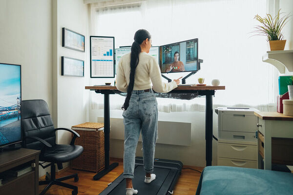 Person standing by a large window taking a brief pause from the desk